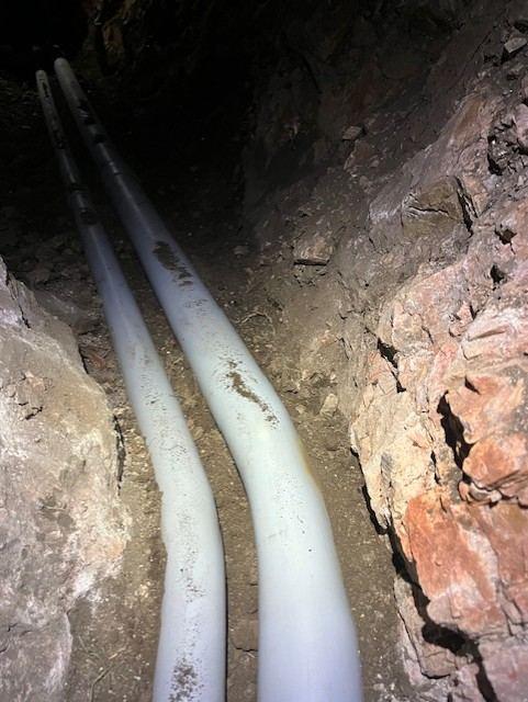 Water line and conduit in a rock trench