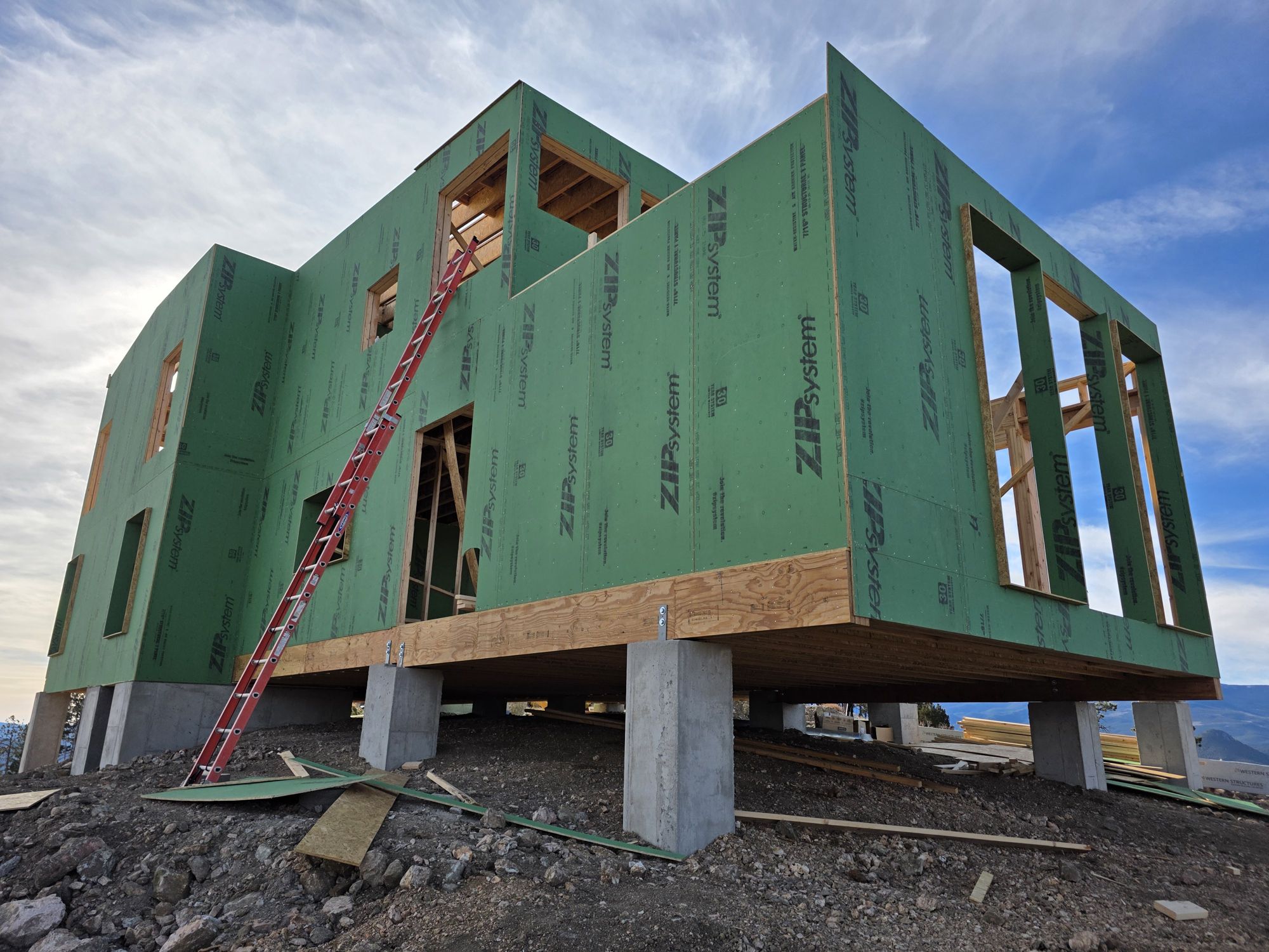 Two-story frame wrapped in green sheathing, set on concrete piers