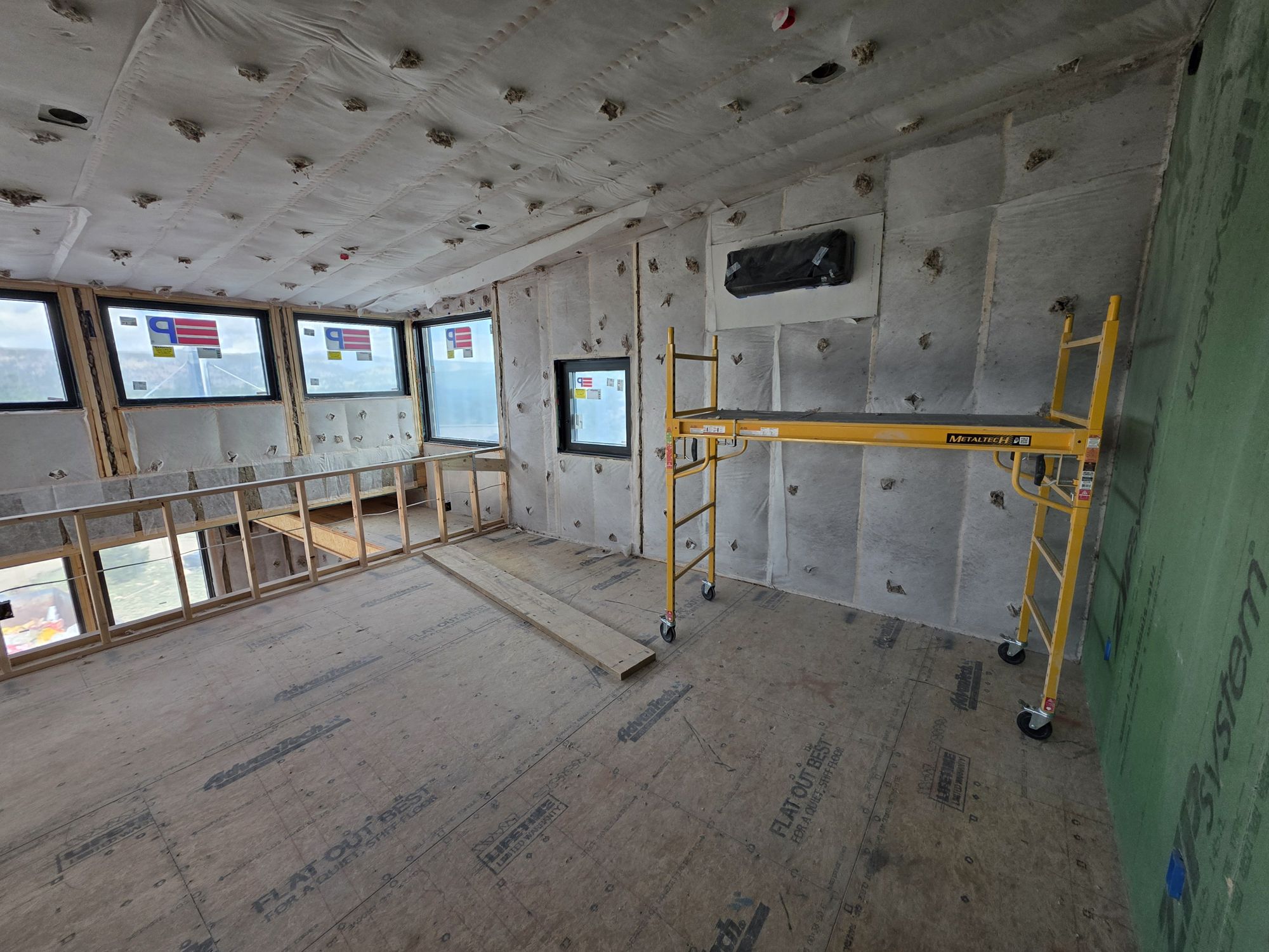 Upper room with insulation installed and corner windows